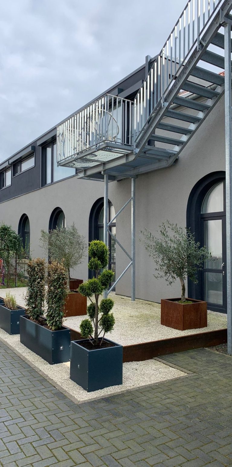 Alte Fabrik Eingang zu einem modernen Gebäude mit Treppe und bepflanzten Töpfen.