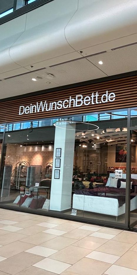 DeinWunschBett.de Shopfront von DeinWunschBett.de mit klarer Beschilderung und modernen Möbeln.